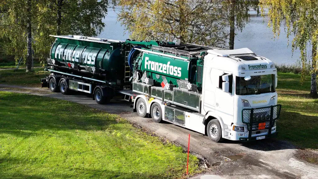 Effektivt transportbilde av tankbil med logo for Franzefoss på vei gjennom naturskjønn landskap.